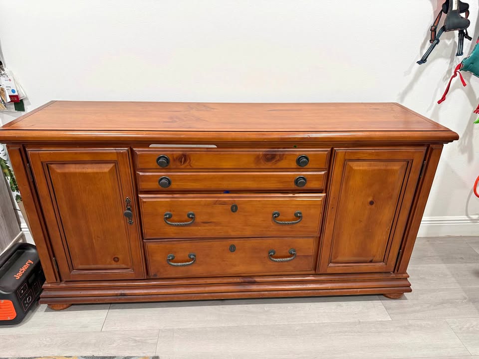 Wooden sideboard with multiple drawers and doors on a gray floor.